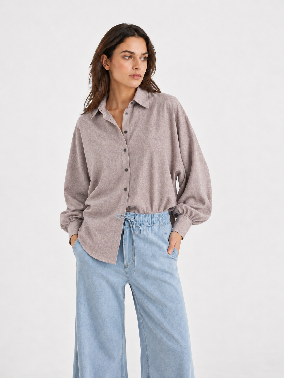 Eine Person, die ein taupefarbenes, langärmeliges Bluse Antonia Slim Flannel-Hemd mit gerafften Manschetten trägt, das in eine hellblaue Jeans mit weitem Bein und Kordelzug in der Taille gesteckt ist.