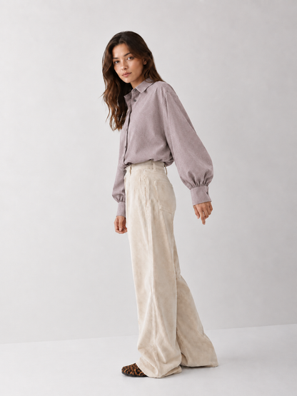 Eine Frau trägt ein taupefarbenes Bluse Antonia Slim Flannel-Hemd, das sie in eine cremefarbene Cordhose mit weitem Bein gesteckt hat.