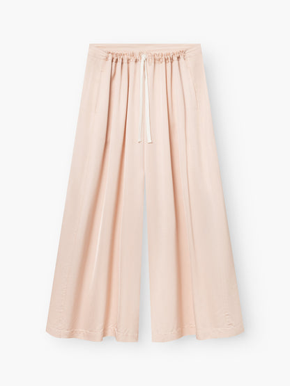 Die Pants Oversize sind weit geschnittene, blushfarbene Damenhosen mit elastischem Kordelzugbund, Vordertaschen und knöchellangem Stoff in Satinoptik - perfekt, um Ihren Stil vor einem weißen Hintergrund aufzuwerten.