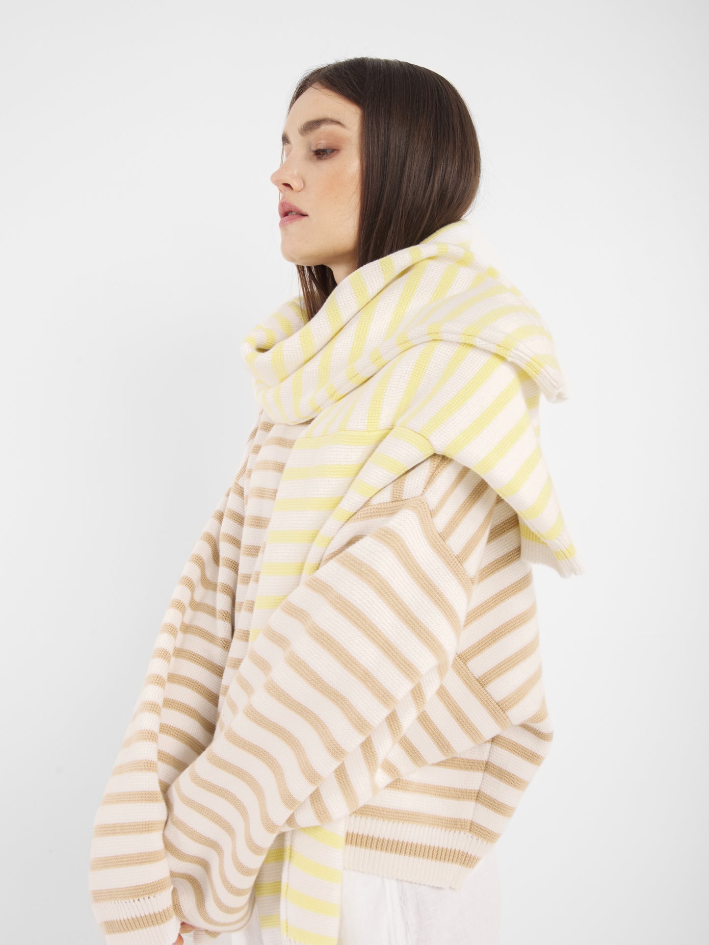 Eine Frau mit glattem braunem Haar trägt den Pullover Sailor Beige Offwhite, der vor einem schlichten weißen Hintergrund steht.