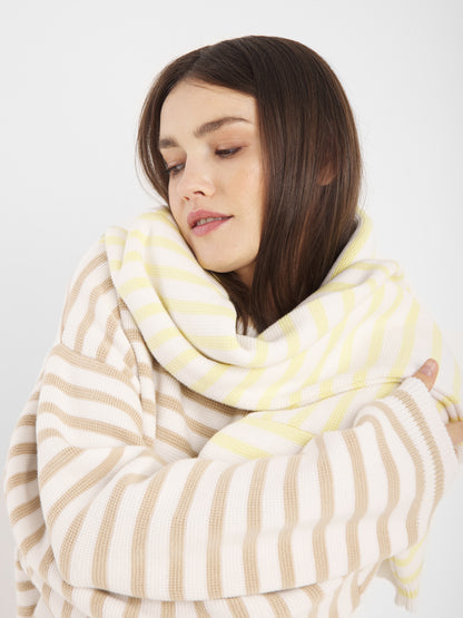 Eine Frau mit langen braunen Haaren trägt den Pullover Sailor Beige Offwhite und blickt gelassen auf einen schlichten weißen Hintergrund.