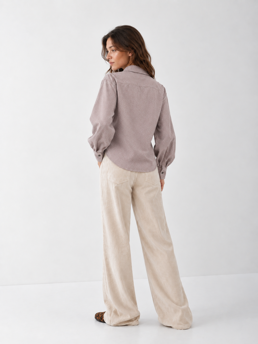 Eine Frau, die ein langärmeliges Bluse Antonia Slim Flannel Taupe-Hemd mit Knöpfen und eine beige Hose mit weitem Bein trägt.
