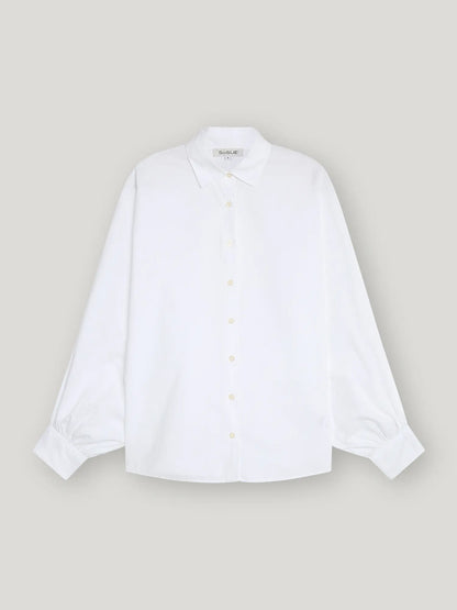 Die Bluse Antonia Slim White ist ein schlichtes, weißes, langärmeliges Button-up-Hemd mit Kragen und geknöpften Manschetten, das auf einem hellgrauen Hintergrund gezeigt wird. Diese weiße Bluse Damen bietet eine entspannte Passform für mühelosen Stil.