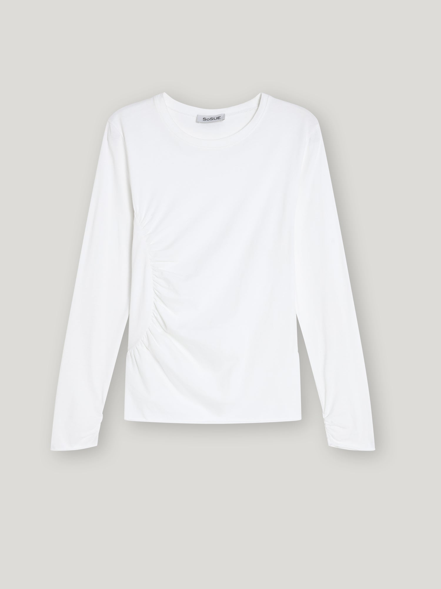 Das Shirt Gathering White ist ein Damen Langarmshirt aus nachhaltiger Baumwolle mit rundem Ausschnitt und dezenter seitlicher Raffung, stilvoll präsentiert vor hellgrauem Hintergrund.