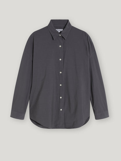 Die Bluse Boyfriend Anthrazit ist eine langärmelige, dunkelgraue Bluse für Damen mit spitzem Kragen, weißen Knöpfen und einer lockeren Passform, die vor einem schlichten hellen Hintergrund gezeigt wird.