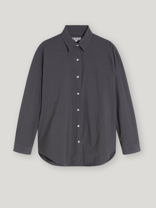 Die Bluse Boyfriend Anthrazit ist eine langärmelige, dunkelgraue Bluse für Damen mit spitzem Kragen, weißen Knöpfen und einer lockeren Passform, die vor einem schlichten hellen Hintergrund gezeigt wird.