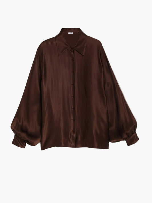 Die Bluse „Antonia Shiny Brown One Size“ ist eine locker sitzende, langärmelige Satinbluse in einem tiefen Braunton mit spitzem Kragen und Knopfleiste vorne, abgebildet vor einem einfarbigen hellgrauen Hintergrund.
