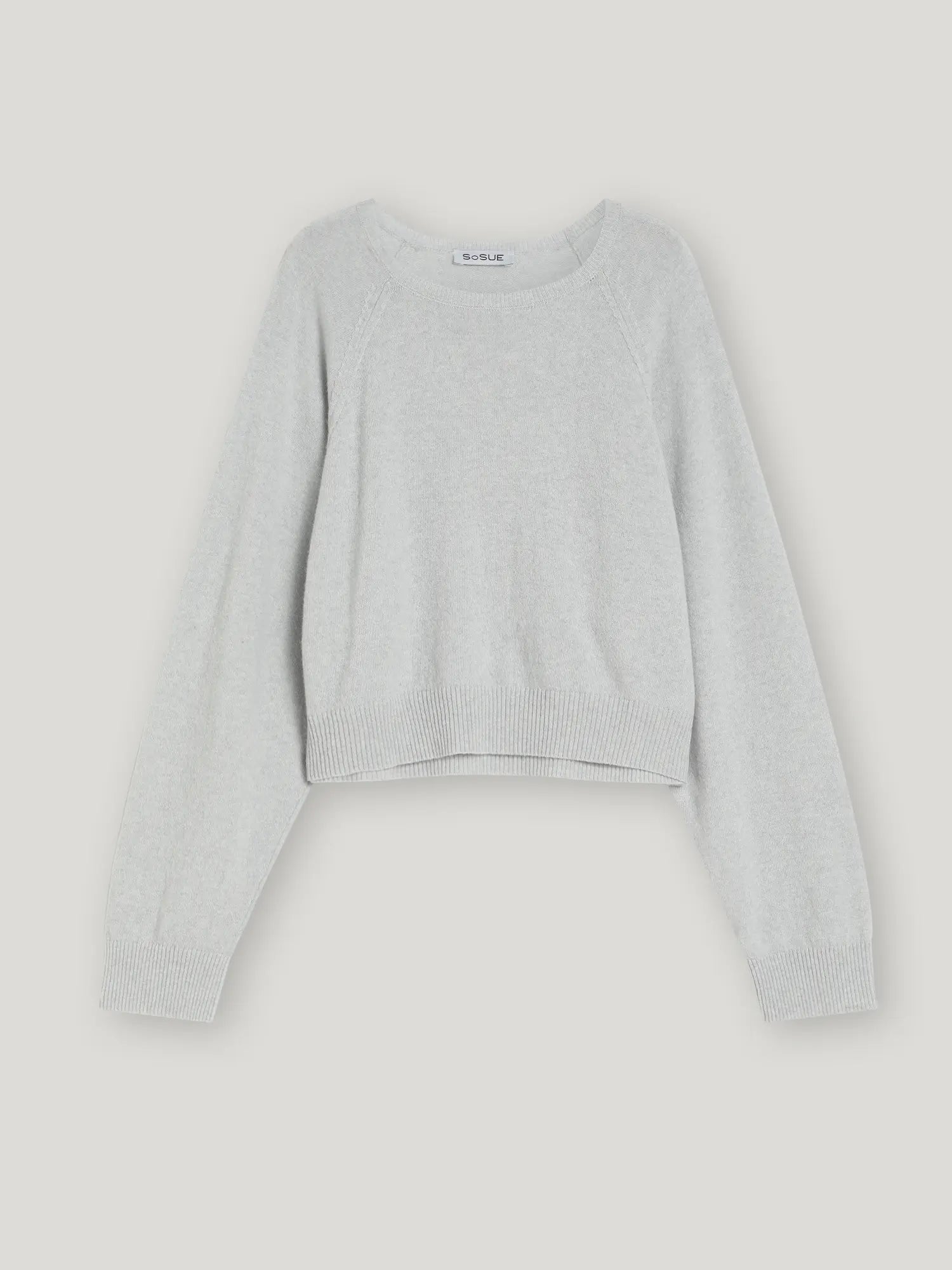 Hellgrauer, langärmeliger, kurz geschnittener Pullover Antonia Grey mit gerippten Bündchen und Saum, flach auf weißem Grund.