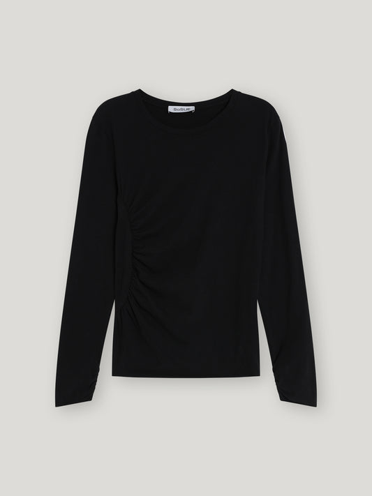 Das Shirt Gathering Black ist ein schlichtes schwarzes Damen-Langarmshirt aus Baumwolle mit Rundhalsausschnitt und dezent gerafftem Seitendetail - ein Must-have für nachhaltige Mode.