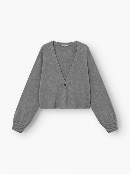Eine graue, langärmelige, kurz geschnittene Strickjacke aus luxuriöser Merinowolle mit tiefem V-Ausschnitt und Ein-Knopf-Verschluss – diese „Antonia Short Cardigan Grau“ wird flach auf weißem Hintergrund präsentiert.