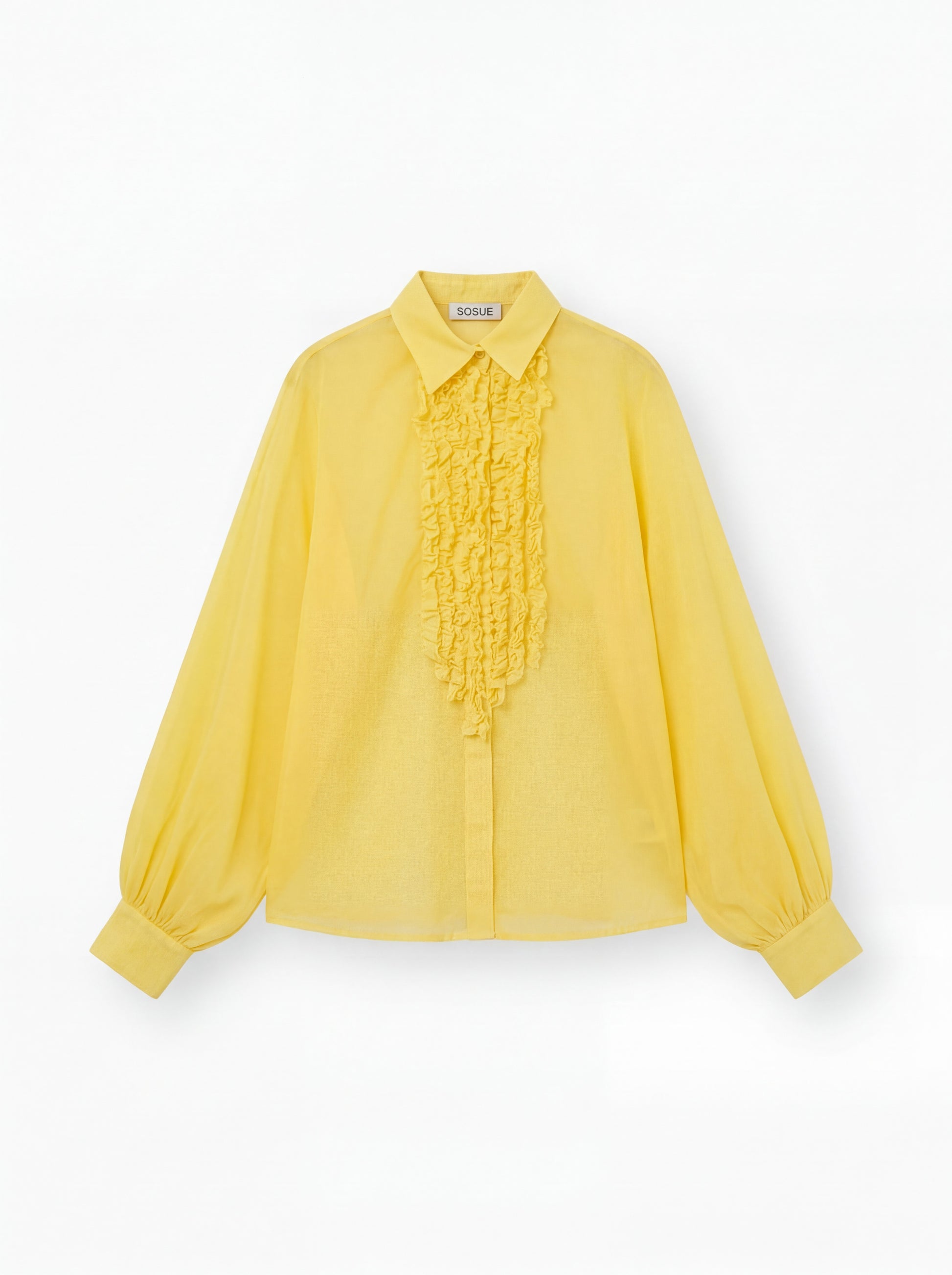 Die gelbe Bluse Antonia Slim Ruffle hat lange Ärmel, einen spitzen Kragen, eine geknöpfte Vorderseite, eine gerüschte Brustpartie und lose geraffte Manschetten. Das SOUGE Label ist auf der Innenseite des Kragens sichtbar.