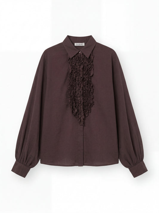 Die Antonia Slim Ruffle Brown ist eine langärmelige, dunkelbraune Bluse mit spitzem Kragen, gerafften Manschetten und Rüschen auf der Vorderseite, die auf weißem Hintergrund abgebildet ist.