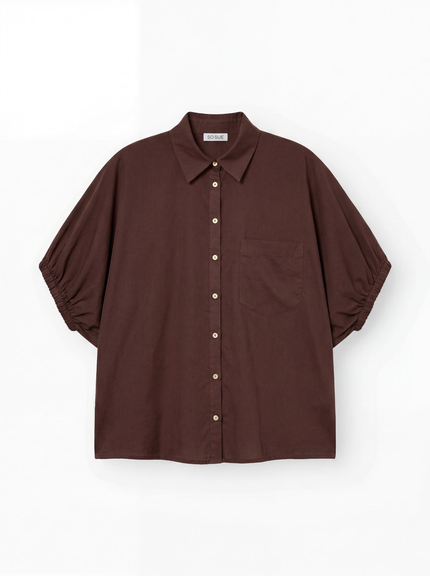 Das Cowboy Collar Voile Brown ist ein locker sitzendes, braunes Hemd zum Knöpfen mit Kragen, kurzen Puffärmeln, die an den Manschetten gerafft sind, und einer einzelnen Brusttasche, abgebildet auf einem schlichten weißen Hintergrund.