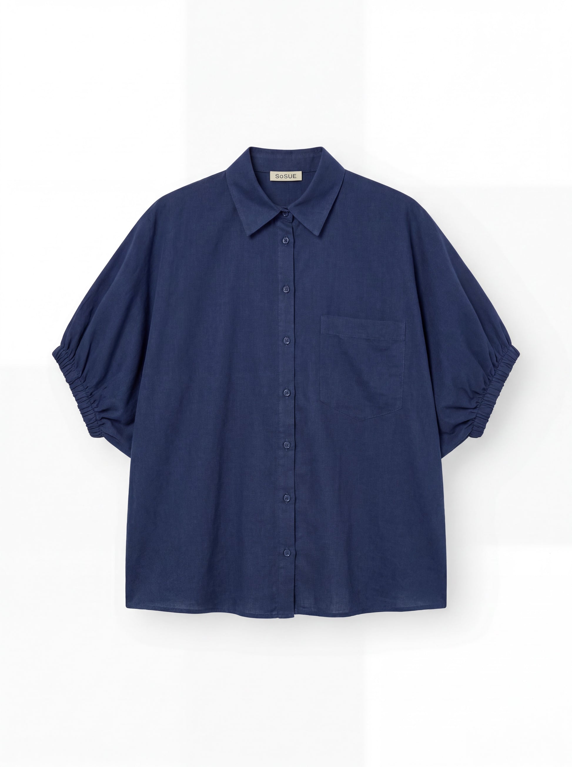 Das Cowboy Collar Voile Navy ist ein locker sitzendes, kurzärmeliges, marineblaues Button-up-Hemd mit einer einzigen Brusttasche und gerafften Ärmeln, das auf einem einfarbig weißen Hintergrund abgebildet ist.