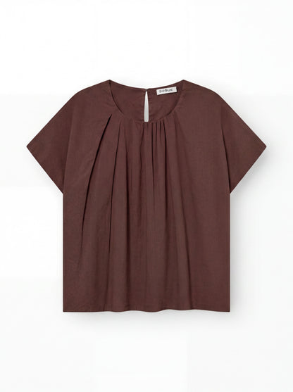 Die Bluse „Tulip Brown“ aus leichtem Baumwollvoile mit kurzen Ärmeln, Rundhalsausschnitt, Plissee vorne und einem kleinen Knopf am Rücken wird vor weißem Hintergrund präsentiert.