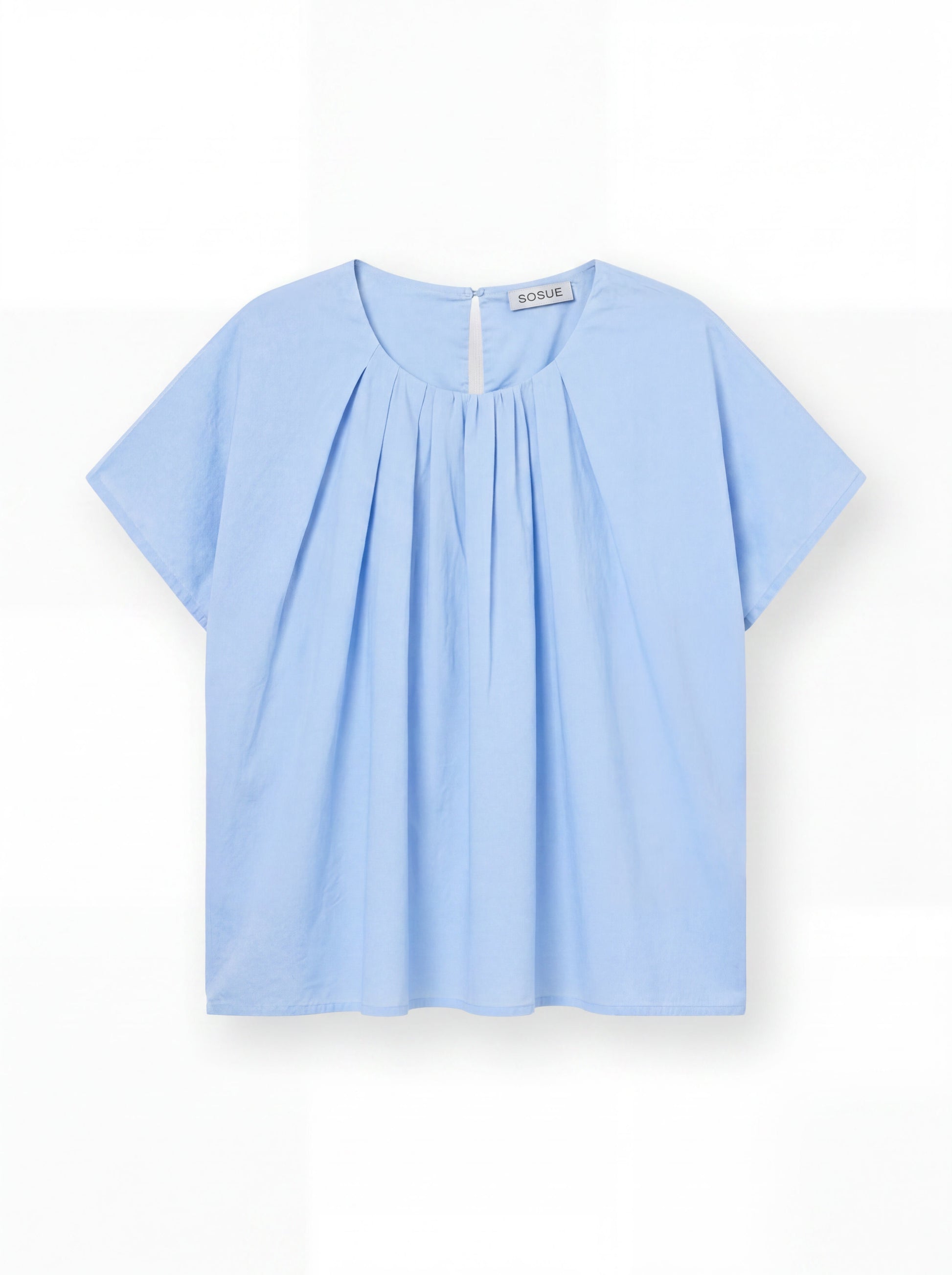 Die Bluse Tulip Light Blue ist eine hellblaue, leichte Baumwollbluse mit kurzen Ärmeln, Rundhalsausschnitt, Frontfalten und kleinem Knopfverschluss am Rücken - präsentiert auf weißem Hintergrund.