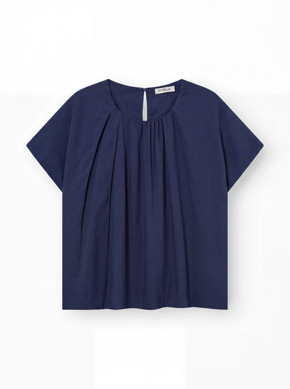 Die Bluse „Tulip Navy“ ist eine kurzärmelige, locker sitzende Damenbluse in Dunkelblau mit Rundhalsausschnitt, Falten auf der Vorderseite und einem kleinen Knopf am Rücken – perfekt als leichte Sommerbluse für warme Tage.