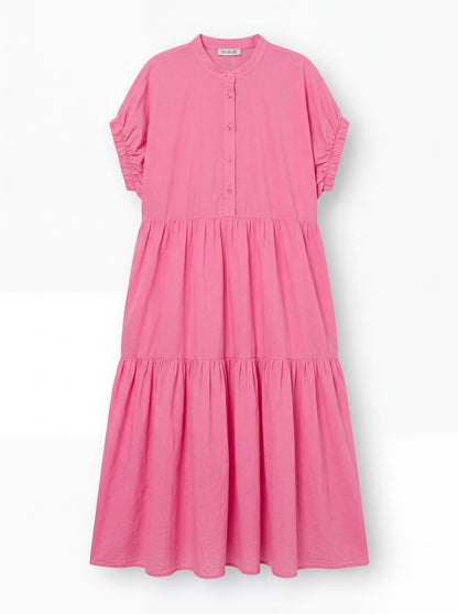 Das Kleid Cowboy Boho Pink ist ein locker sitzendes, knöchellanges Baumwoll-Voile-Kleid mit kurzen Rüschenärmeln, einem geknöpften Ausschnitt und einem gestuften, gerafften Rock, das auf einem einfarbig weißen Hintergrund abgebildet ist.