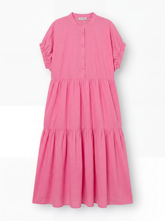 Das Kleid Cowboy Boho Pink ist ein locker sitzendes, knöchellanges Baumwoll-Voile-Kleid mit kurzen Rüschenärmeln, einem geknöpften Ausschnitt und einem gestuften, gerafften Rock, das auf einem einfarbig weißen Hintergrund abgebildet ist.