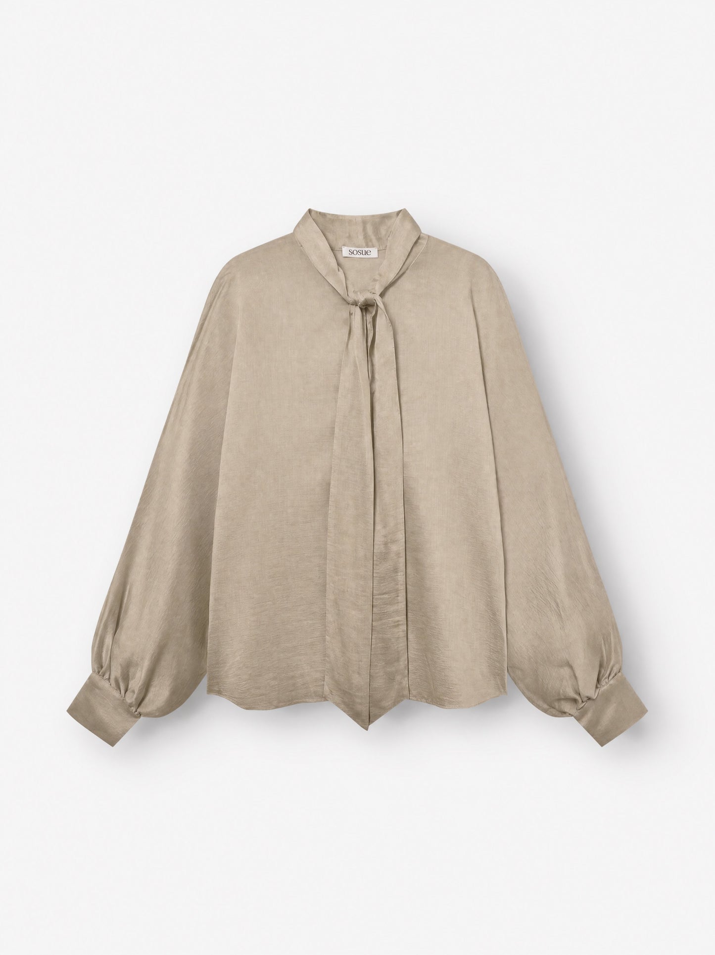 Die Bluse „Antonia Bow Taupe“ besticht durch ihren beigen Farbton, lange Ärmel, eine lockere Passform, einen Bindegürtel am Halsausschnitt, geknöpfte Ärmelbündchen und einen dezenten Schimmer – hier auf weißem Hintergrund abgebildet.