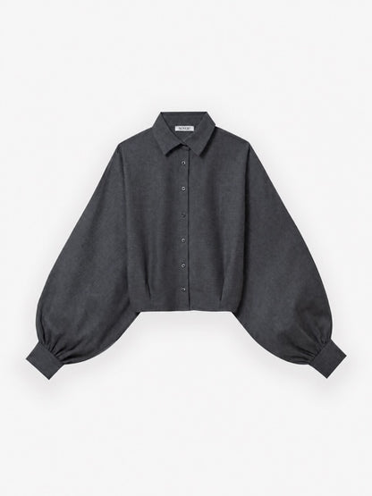 Die Bluse „Antonia Short Flanell Anthrazit“ ist eine dunkelgraue, kurz geschnittene Bluse mit einer besonders weiten Silhouette und langen Ballonärmeln mit breiten Manschetten. Sie besteht aus weichem Baumwollflanell und wird vor weißem Hintergrund präsentiert.