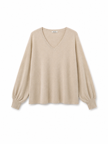 Der Pullover „Antonia“ mit V-Ausschnitt in der Farbe „Powder“ (Beige) wird vor einem weißen Hintergrund präsentiert. Er verfügt über lange Ärmel, eine lockere Passform und elegante Ballonärmel. Dieser Pullover aus Merinowolle verbindet zeitlosen Stil mit außergewöhnlichem Tragekomfort.