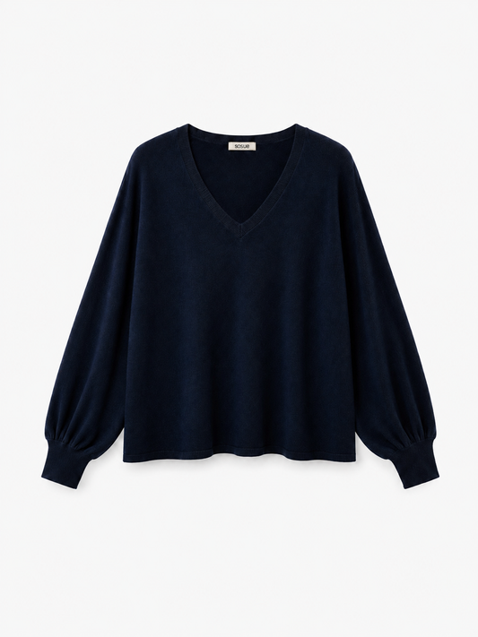 Der Pullover „Antonia“ mit V-Ausschnitt in Dunkelblau ist eine langärmelige, dunkelblaue Bluse mit V-Ausschnitt und lockeren, leicht gepufften Ärmeln mit Manschetten. Er wird vor einem weißen Hintergrund gezeigt.