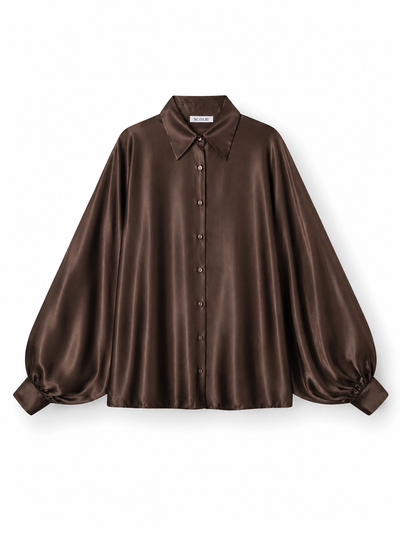 Die Bluse „Antonia Shiny Brown“ in Einheitsgröße wird elegant vor einem weißen Hintergrund präsentiert und zeichnet sich durch einen spitzen Kragen, eine Knopfleiste vorne sowie lange, voluminöse Ärmel mit breiten Manschetten aus. Sie wurde fachmännisch als „Bluse Braun“ gefertigt und wird mit Stolz in Portugal hergestellt.