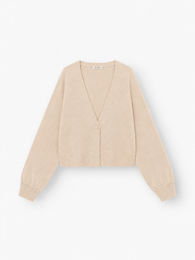 Die Antonia Short Cardigan Puder ist eine beigefarbene, langärmelige Damen-Strickjacke mit V-Ausschnitt, gerippten Bündchen und Saum sowie einem Ein-Knopf-Verschluss. Sie besteht aus einer luxuriösen Merinowolle-Kaschmir-Mischung und wird vor einem weißen Hintergrund präsentiert.